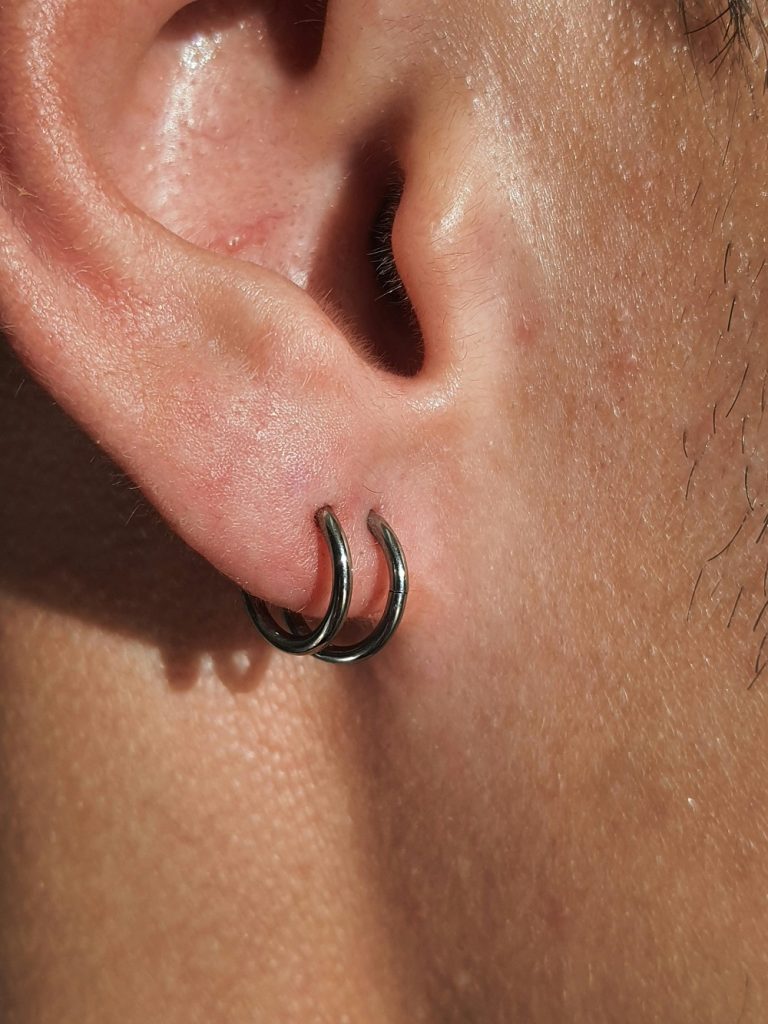Two ear piercings on a man's right ear.