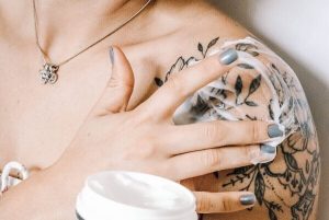 A girl putting a cream on her tattoo