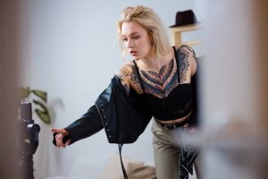 Blonde tattooed woman in black leather jacket.