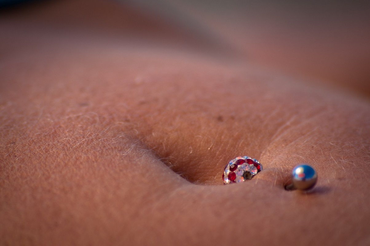 A pink piercing on a stomach.