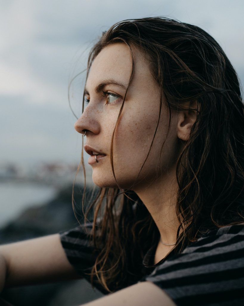 Thoughtful woman with wet hair looking away with piercings on her lip and nose.