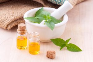 Small bottles of natural oil with herb cup behind them.