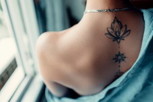 A woman with back half covered and a tattoo on her spine.
