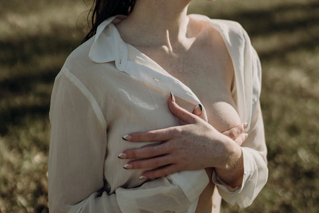 Woman in white shirt holding her breasts