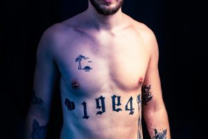 Topless man with tattoos and nipple rings