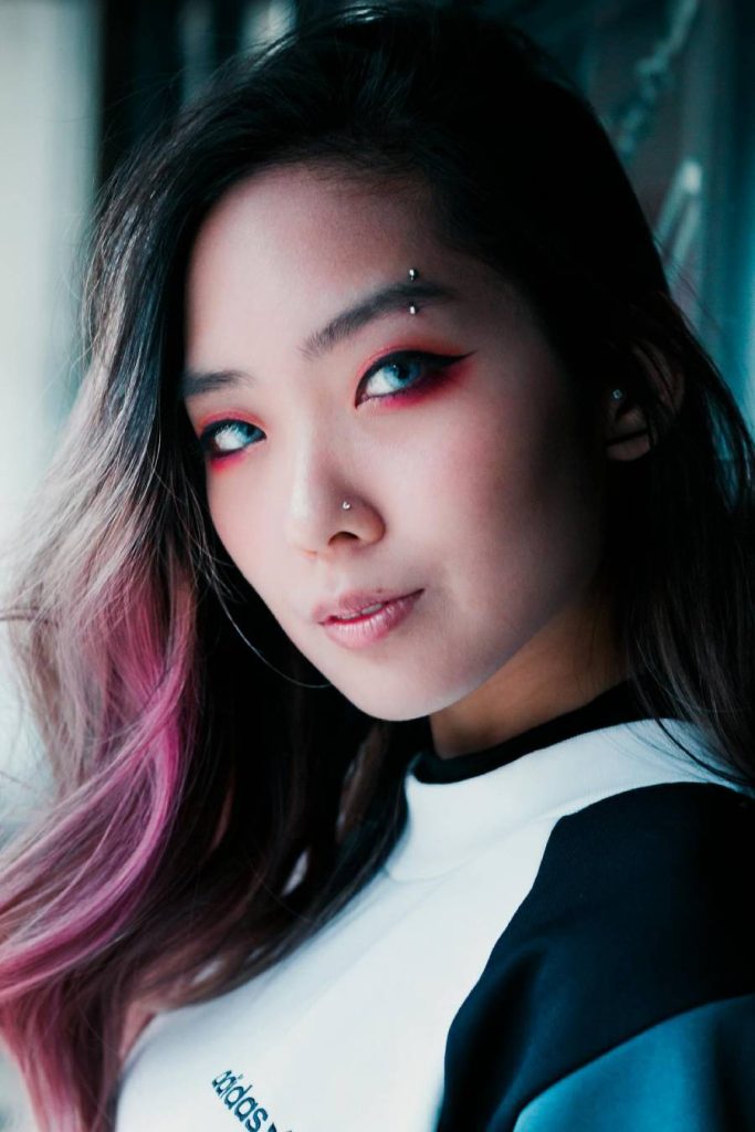 Woman with multi colored hair, nose piercing and eyebrow piercing