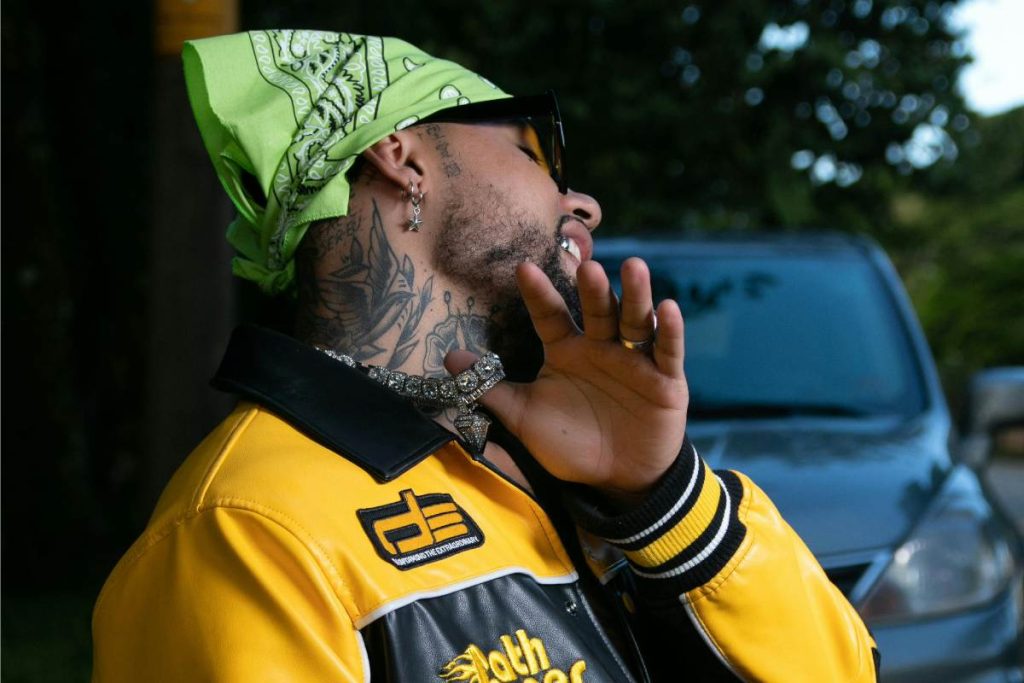 A man with bird and rose neck tattoo with yellow jacket