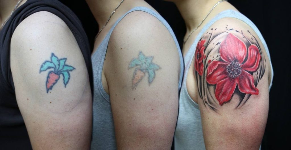 Small carrot tattoo covered with big red flower tattoo