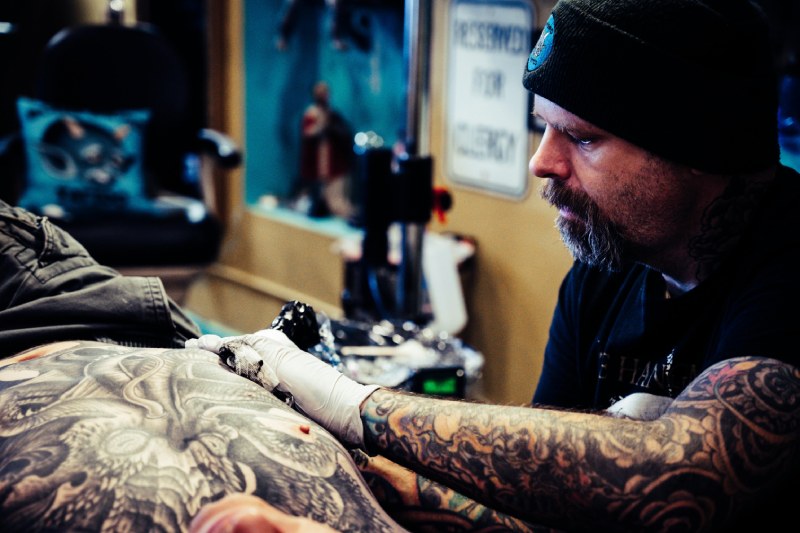 Tattoo artist making cover up tattoo in a tattoo studio