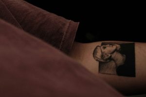 Man with red shirt and inner arm tattoo