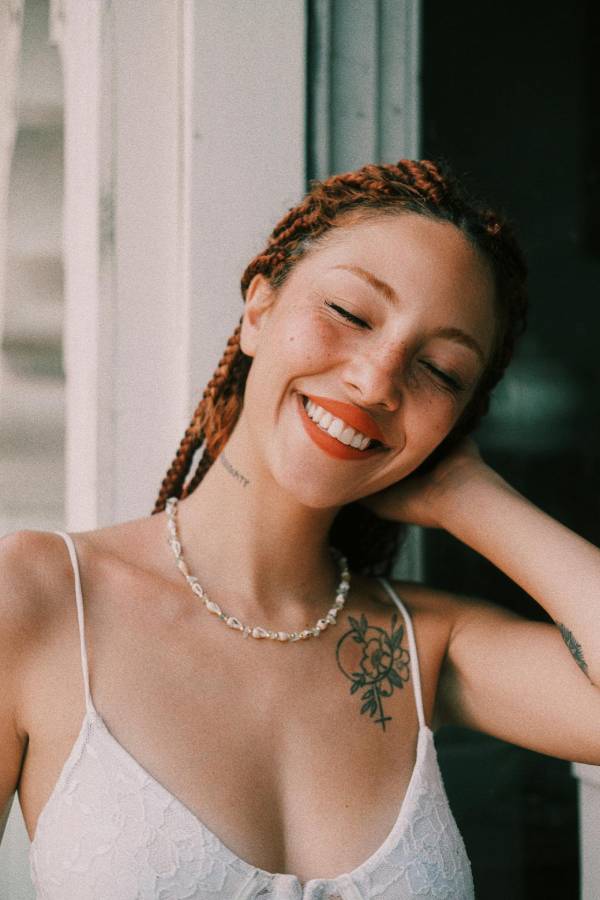 Woman in red shirt smiling with a front shoulder tattoo